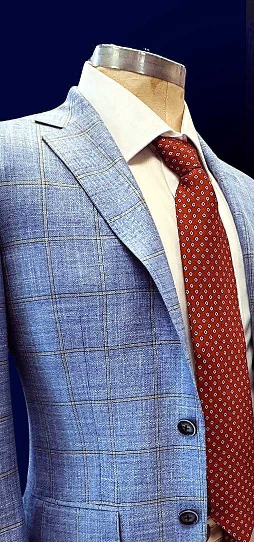 A light blue suit, white shirt and rust tie on a form
